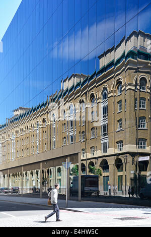 Bricks and mortar building reflected in glass walls of new modern office block Stock Photo