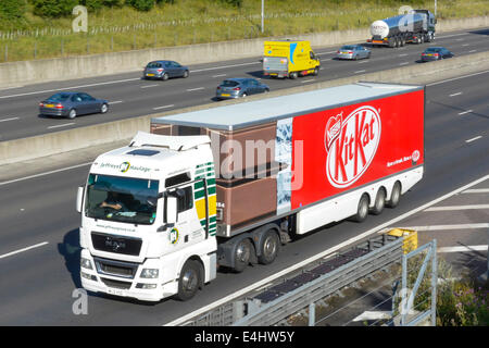 Nestlé Kit Kat chocolate bar & wrapper graphics on side of articulated trailer advertising product behind hgv lorry truck driving along uk  motorway Stock Photo