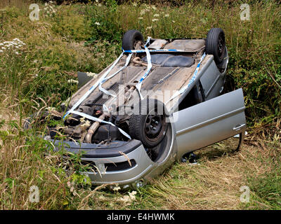 Crashed car upside down in a ditch beside the road, Westward Ho!, Devon, UK Stock Photo