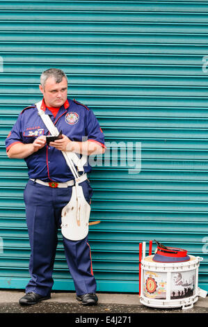 An Orange Bandsman uses his mobile phone while waiting for the parade to begin. Stock Photo