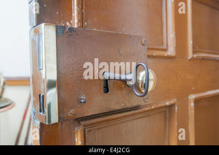 Heavy brass lock on the inside of a door, with a large old-fashioned key. Stock Photo