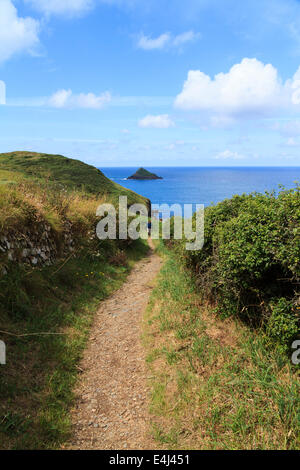 A walker on the South West Coast Path, North Cornwall at Pentire Point, looking towards The Mouls Stock Photo
