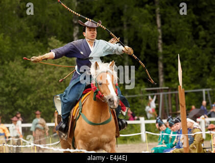 Riding samurai spurs his horse in the traditional Japanese Yabusame ceremony of mounted archery performed in Helsinki. Stock Photo