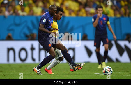 Brasilia, Brazil. 12th July, 2014. Netherlands' Bruno Martins Indi (front) vies with Brazil's Willian during the third place play-off match between Brazil and Netherlands of 2014 FIFA World Cup at the Estadio Nacional Stadium in Brasilia, Brazil, on July 12, 2014. Credit:  Guo Yong/Xinhua/Alamy Live News Stock Photo