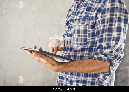 Man holding digital tablet computer and taping the touch screen of modern 10 inch display gadget. Stock Photo
