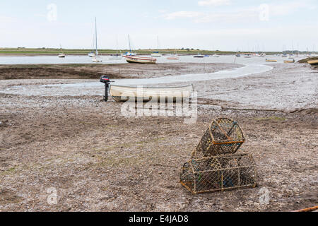Lobster pots stacked in a tidal creek at low tide at Brancaster Staithe, a small fishing village on the north Norfolk coast, UK Stock Photo