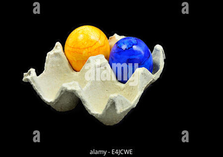two colorful easter eggs in a cardboard box, close up, isolated on black background Stock Photo
