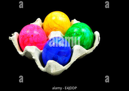 four colorful easter eggs in a cardboard box, close up, isolated on black background Stock Photo