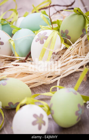 Collection of four hand decorated colourful green Easter eggs with different patterns displayed in straw, close up view Stock Photo