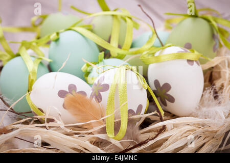 Collection of four hand decorated colourful green Easter eggs with different patterns displayed in straw, close up view Stock Photo