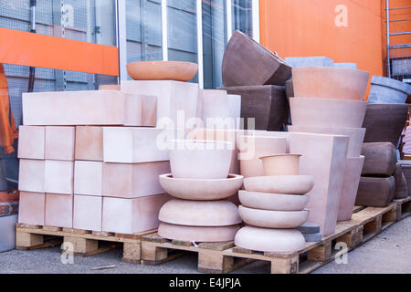 Glazed and unglazed ceramic flower pots in a variety of sizes and colors stacked on wooden pallets outside a pottery, warehouse Stock Photo