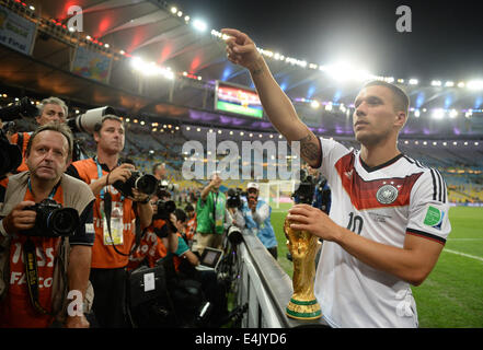 Rio de Janeiro, Brazil. 13th July, 2014. Germany's Lukas Podolski celebrates on the pitch with the World Cup trophy after winning the FIFA World Cup 2014 final soccer match between Germany and Argentina at the Estadio do Maracana in Rio de Janeiro, Brazil, 13 July 2014. Photo: Andreas Gebert/dpa/Alamy Live News Stock Photo