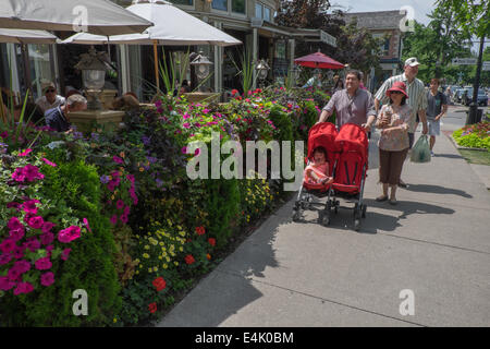 Tourists walk by one of many colourful floral displays which can be found in the historic old town of Niagara-on-the-Lake, Ontario, Canada. Stock Photo