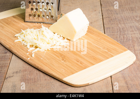 Fresh Parmesan cheese with a metal grater on a cutting board Stock Photo