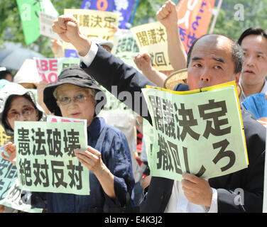 Tokyo, Japan. 14th July, 2014. People raise their fists and shout slogans during a demonstration against the Japanese governments' move to approve the right for the collective self-defense by reinterpretating the pacifist Constitution in front of the Parliament Building in Tokyo, Japan, July 14, 2014. Around 400 people took part in the demonstration. © Stringer/Xinhua/Alamy Live News Stock Photo