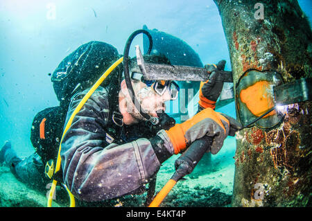 Commercial divers attach a zinc anode to a brine discharge pipe from a desalination plant on the seabed to a distance of 300 met Stock Photo