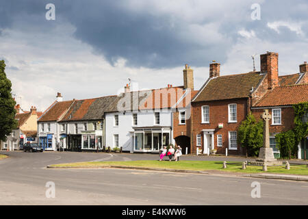 Town centre and green of Burnham Market, a small town in north Norfolk, UK, row of terraced houses and shops and war memorial Stock Photo