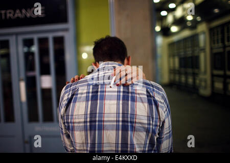 A couple embracing and woman with a cigarette on a night out in Cardiff, Wales, UK Stock Photo