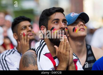Toronto, Canada. 13th July, 2014. German fans react while watching the 2014 FIFA World Cup final between Germany and Argentina on the street in Toronto, Canada, July 13, 2014. Germany defeated Argentina 1-0 and won its fourth World Cup title on Sunday. © Zou Zheng/Xinhua/Alamy Live News Stock Photo