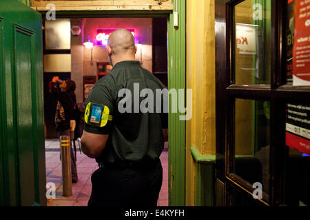 A security guard in a pub doorstep at night in Cardiff, Wales, UK Stock Photo