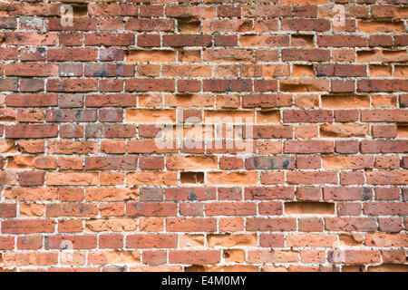 Weathered, crumbling red bricks and brickwork in an old eroded brick wall needing re-pointing and exposing the mortar Stock Photo