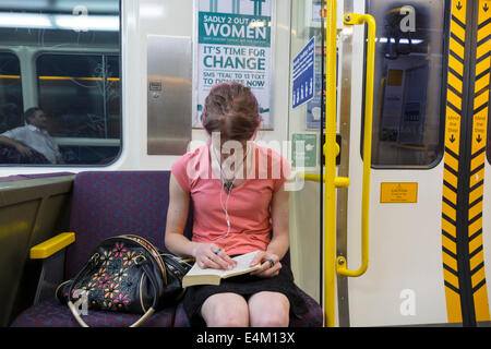 Brisbane Australia CBD,Central Station,QueenslandRail,Rail,railway,train,woman female women,passenger passengers rider riders,sitting,reading,pocketbo Stock Photo