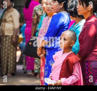 A young nun attends an Alms Ceremony with her family at the Maha Aung Mye Bonzan Monastery in Mandalay, Myanmar. Stock Photo