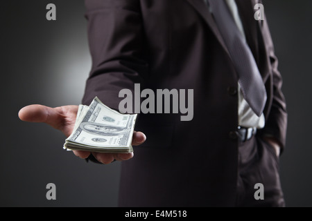 businessman in suit holding money on dark background Stock Photo