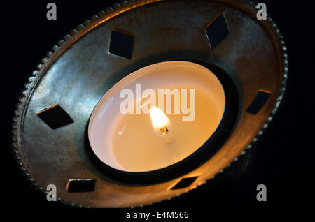 burning tea light in a silver candlestick holder, close up, isolated on black background Stock Photo