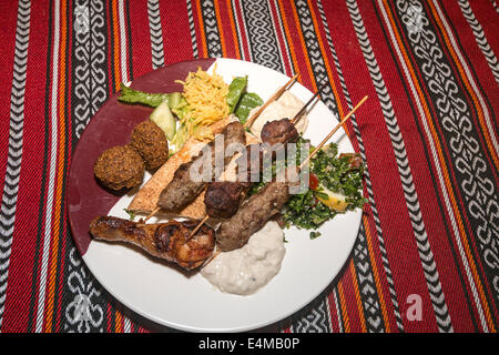 Dinner at the Desert Safari outside Dubai, UAE. Grilled skewers of lamb, beef, chicken, falafal, tabouli and hummus Stock Photo