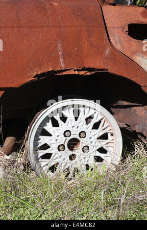 Alloy wheel on a burnt out, dumped and stolen car. Stock Photo