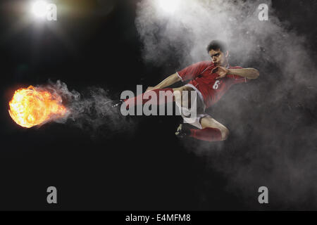 Soccer Player Kicking The Ball In Mid-Air Stock Photo