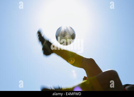 Football player kicking ball in mid-air Stock Photo