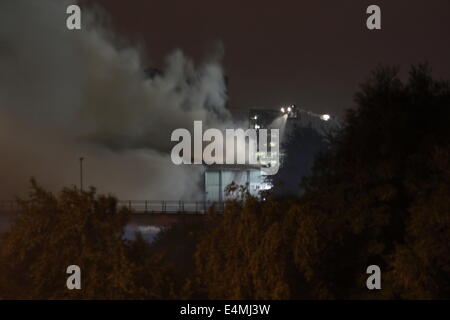 London, UK. 15th July, 2014. Some 70 FireFighters from across London called to tackle a fire in a waste transfer station on Scarab Close, Canning Town East London. Crews from as far away as Tooting were called to the scene to deal with the blaze which involved several hundred tonnes of waste materials. Thick smoke billowed from the blaze which resulted in LFB warning local residents to keep doors and windows closed. It is not yet known if the closure of close by Silvertown fire station exasperated the blaze as crews had to travel from further afield to the incident. Credit:  HOT SHOTS/Alamy Li Stock Photo