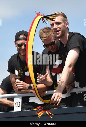 Berlin, Germany. 15th July, 2014. Benedikt Hoewedes (L-R), Christoph Kramer and Per Mertesacker celebrate on the open team bus during the reception of the German national soccer team in Berlin, Germany, 15 July 2014. The German team on 13 July 2014 had won the Brazil 2014 FIFA Soccer World Cup final against Argentina by 1-0 to win the title for the fourth time after 1954, 1974 and 1990. Photo: JENS KALAENE/DPA/Alamy Live News Stock Photo