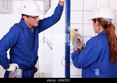 Male electrician supervising female apprentice Stock Photo