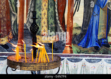 Lighted candles in front of the monastery fresco Stock Photo