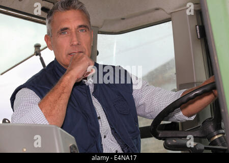 a farmer in a tractor cabin is driving Stock Photo