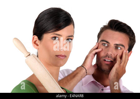 Angry woman threatening man with rolling pin Stock Photo