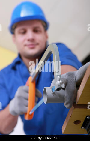 Plumber sawing grey plastic pipe Stock Photo