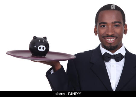 Waiter holding a piggy bank on his tray Stock Photo