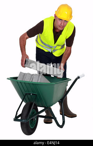 Mason carrying bricks in wheel barrow Stock Photo