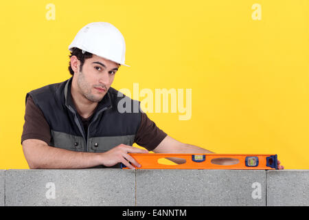 Builder with a spirit level on a wall Stock Photo