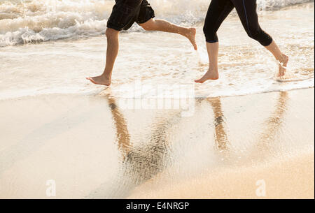 USA, Florida, Palm Beach, Couple running on beach, low section Stock Photo