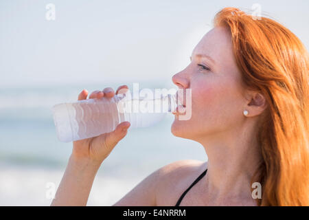 View of woman drinking water on beach Stock Photo