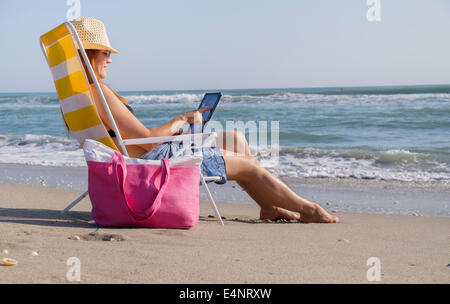 USA, Florida, Palm Beach, Woman sitting on deckchair and using laptop Stock Photo
