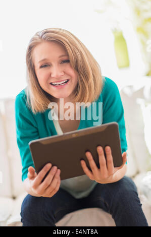 Portrait of woman on sofa holding digital tablet Stock Photo