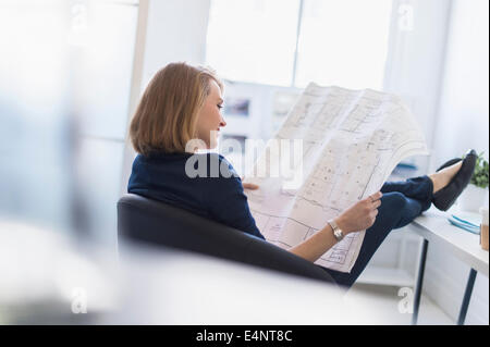 Business woman looking at blueprint in office Stock Photo