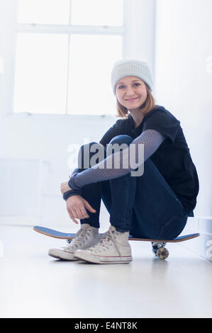 Portrait of young woman sitting on skateboard Stock Photo