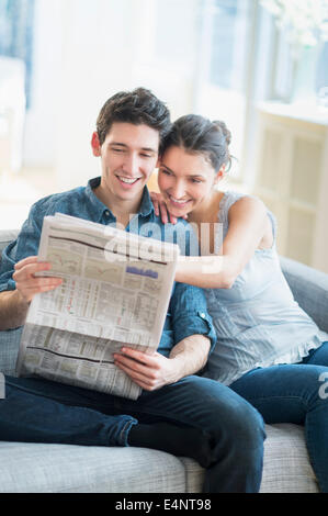 Couple reading newspaper on sofa Stock Photo